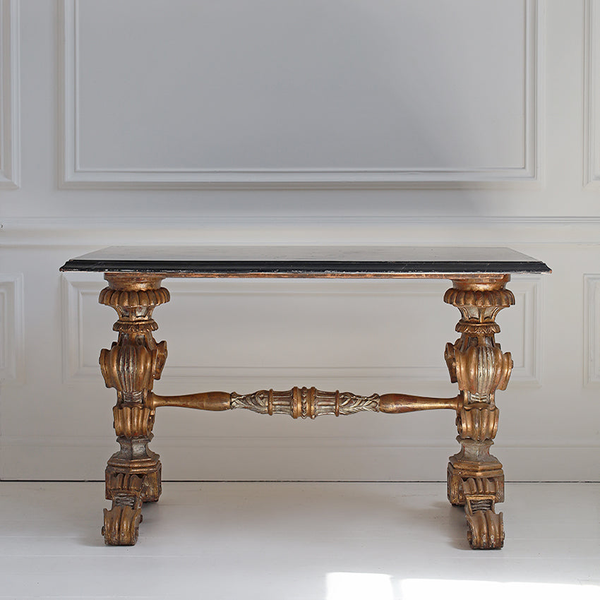Decorative table with ornate legs and marble top against a white wall
