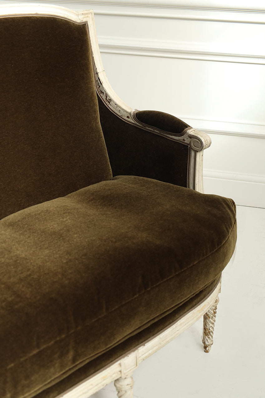 Brown upholstered chair with white frame against a white wall