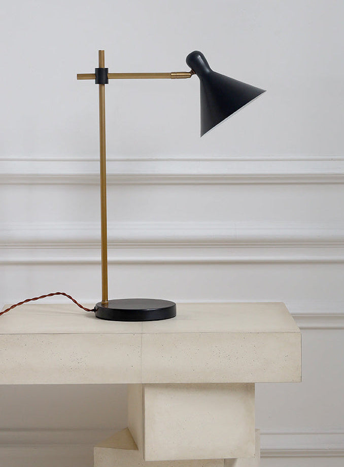 Modern black and gold lamp on a white surface with a neutral background