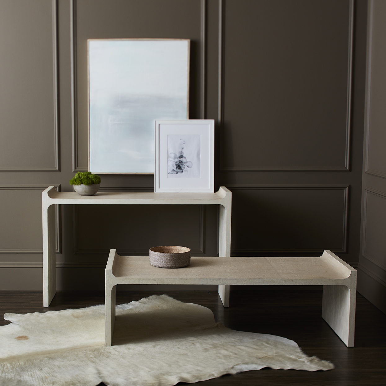 Minimalist interior with a wooden bench, table, and framed picture against a dark wall.