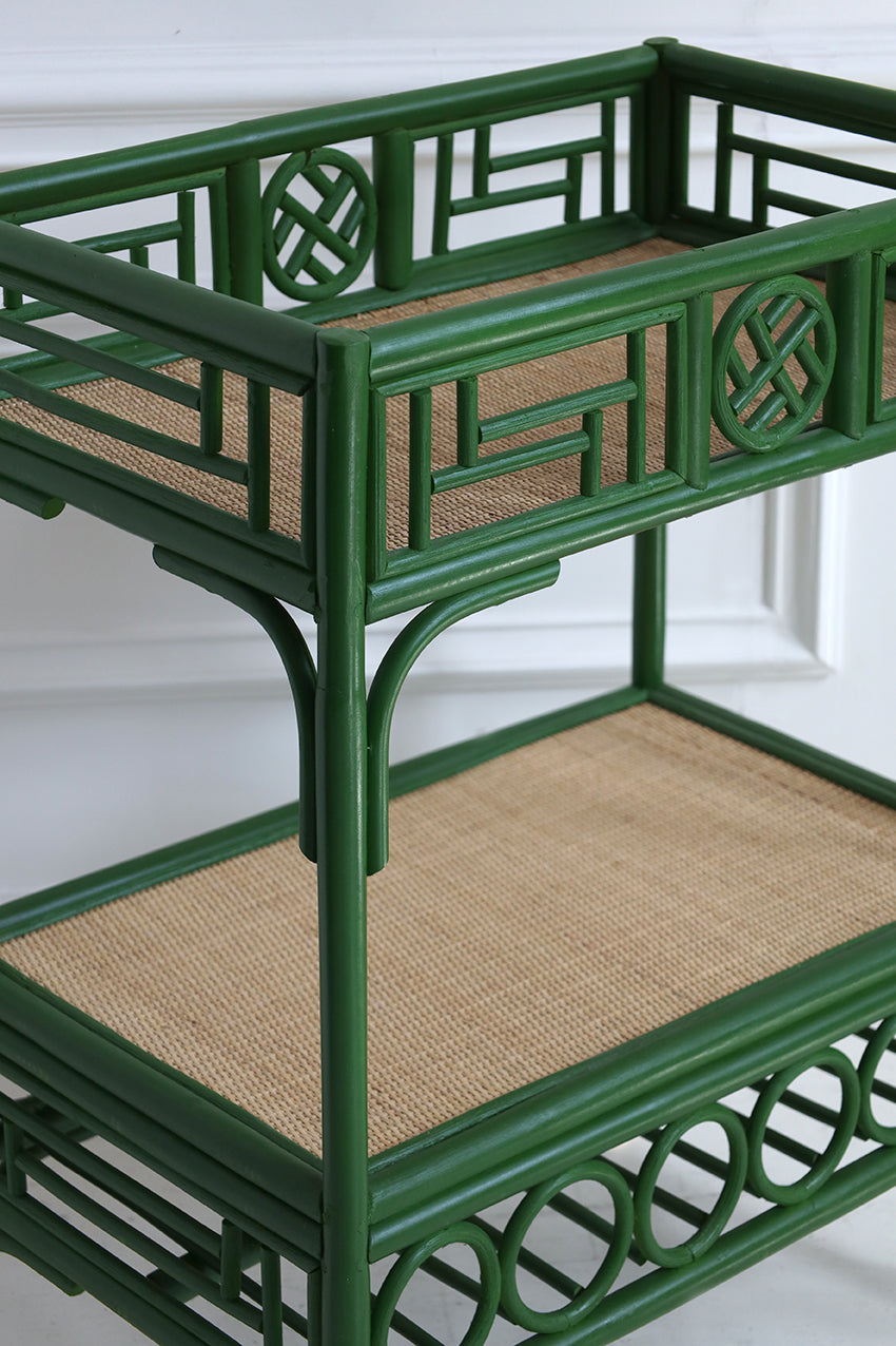 Green rattan serving cart with woven shelves on a white background