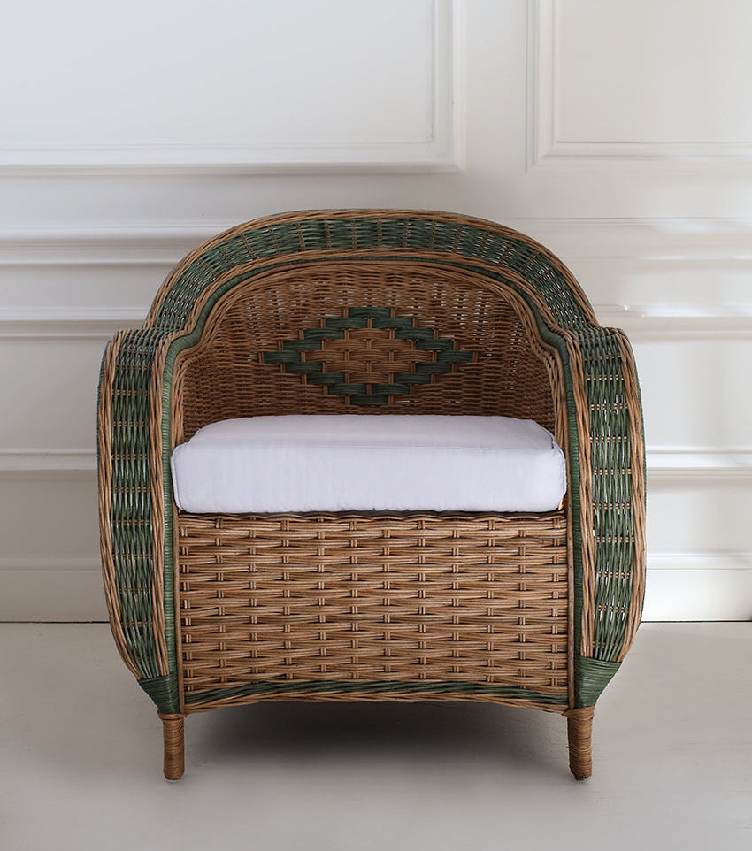handcrafted wicker armchair with a white cushion on a light wooden floor.