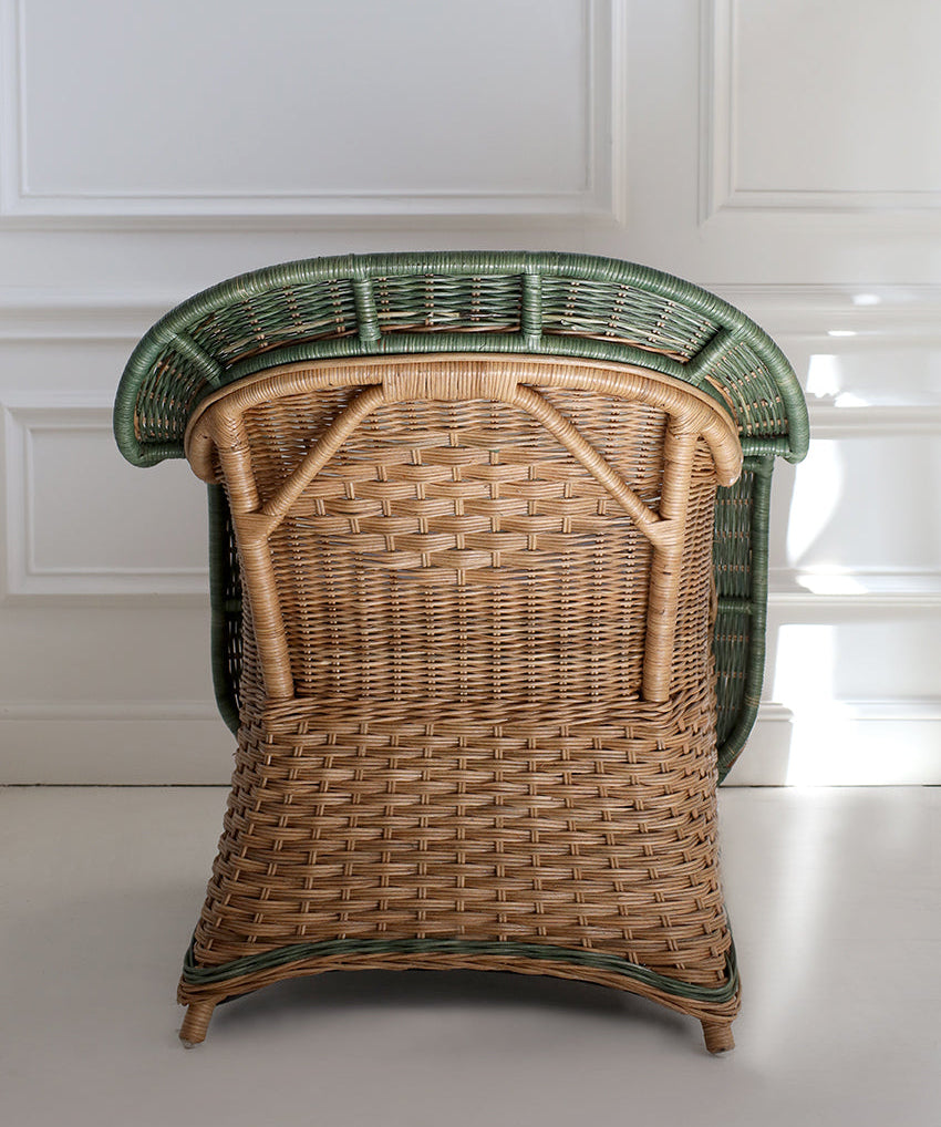 handcrafted wicker chair with green top against a white paneled wall