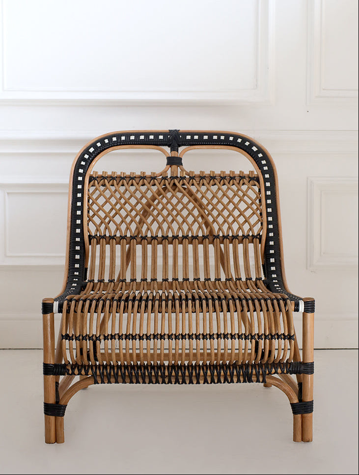 handcrafted wicker chair with black accents against a white wall