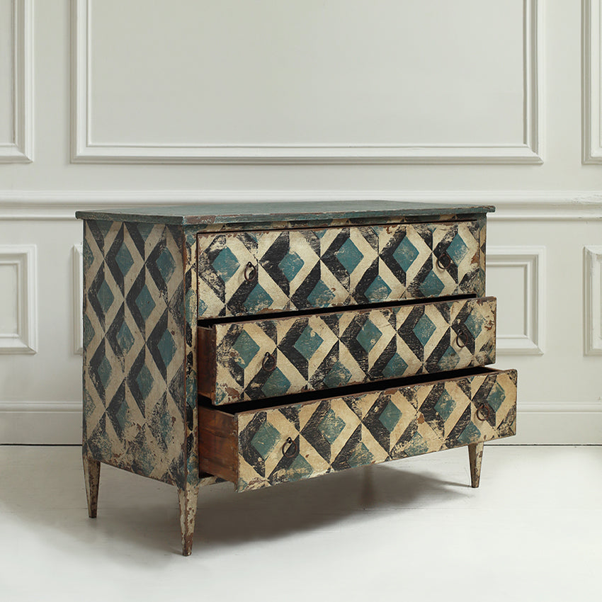 Wooden dresser with geometric pattern in a room with white paneled walls.