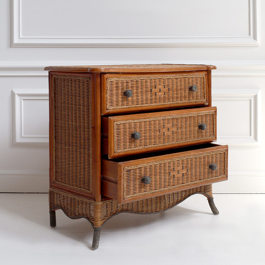 Wicker dresser with three drawers against a white wall