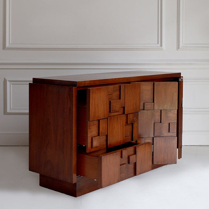 Wooden sideboard with geometric design against a white paneled wall