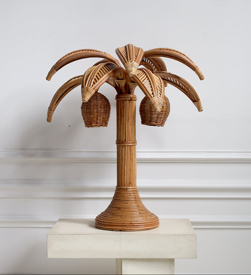 Wicker palm tree lamp on a white pedestal against a light gray background