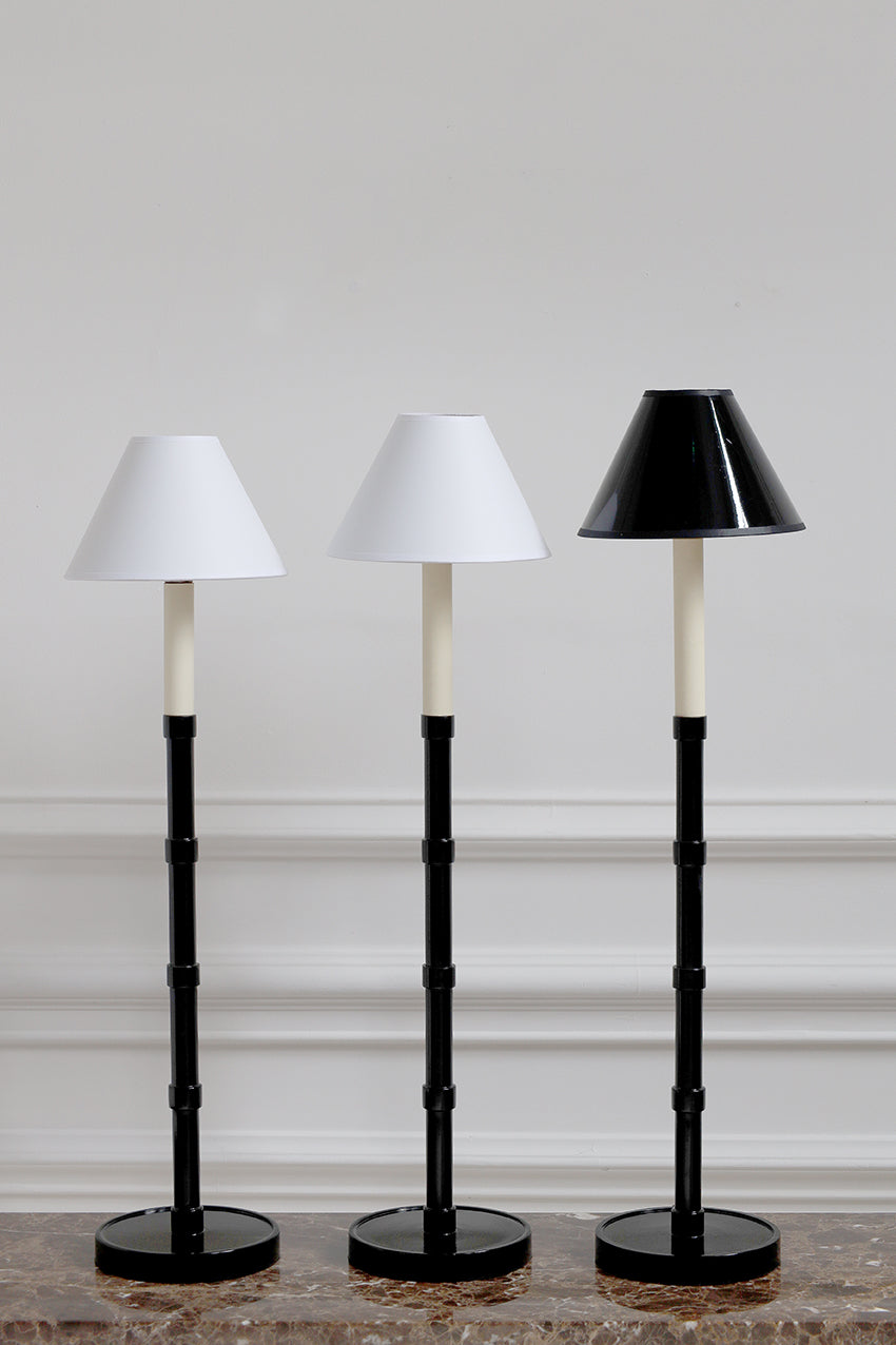 Three black and white floor lamps with different shade designs on a neutral background.