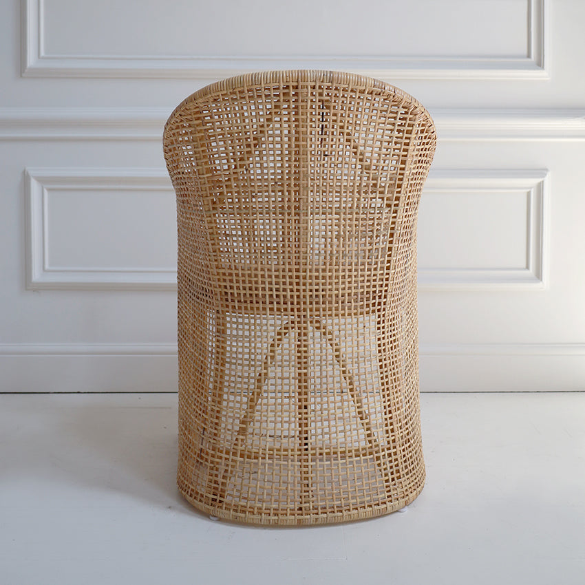 Woven rattan stool against a white paneled wall