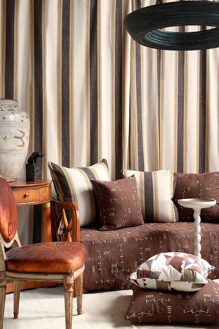 Living room with striped curtains, brown sofa, and wooden chair.