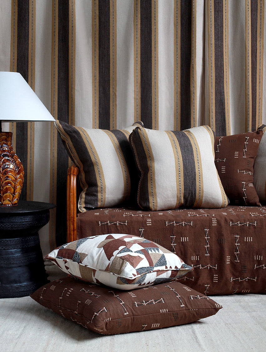 Sofa with patterned cushions against a striped curtain background
