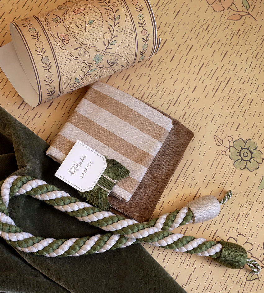 Green fabric, striped box, and embroidered cylindrical object on a textured surface