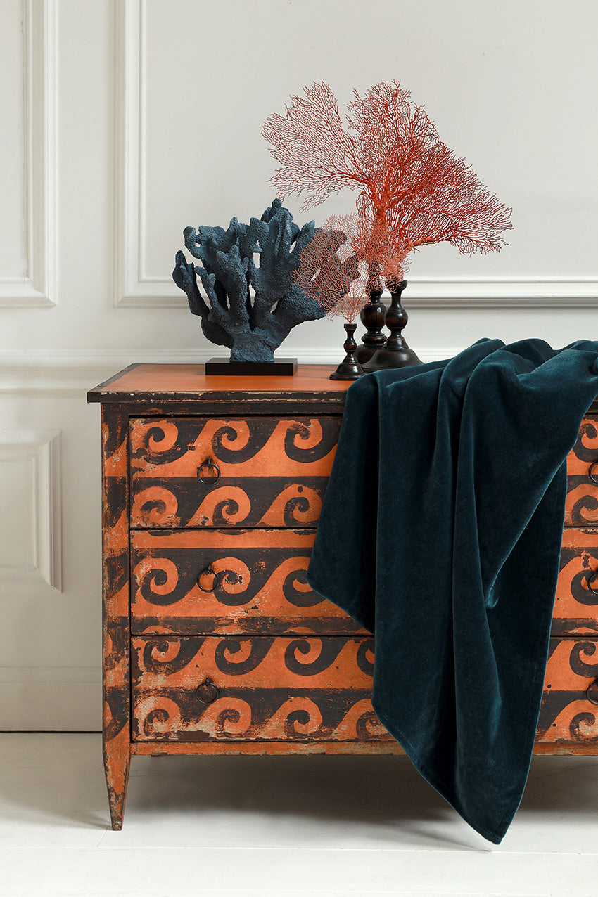 Decorative chest with wavy pattern, dark blue blanket, and coral sculptures on a white background