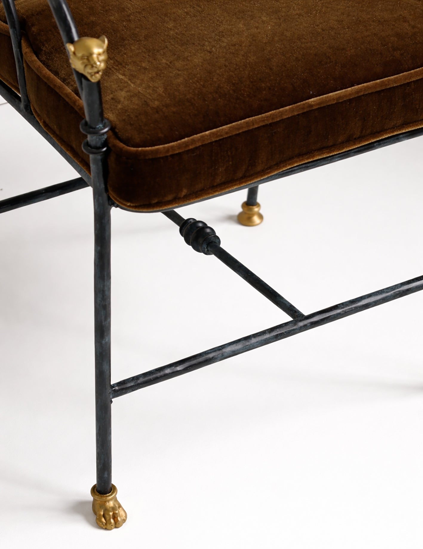 Brown cushioned chair with black metal frame and gold accents on a white background