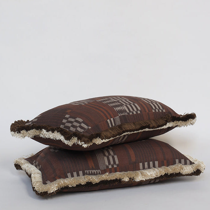 Two brown patterned pillows with white trim on a light gray background