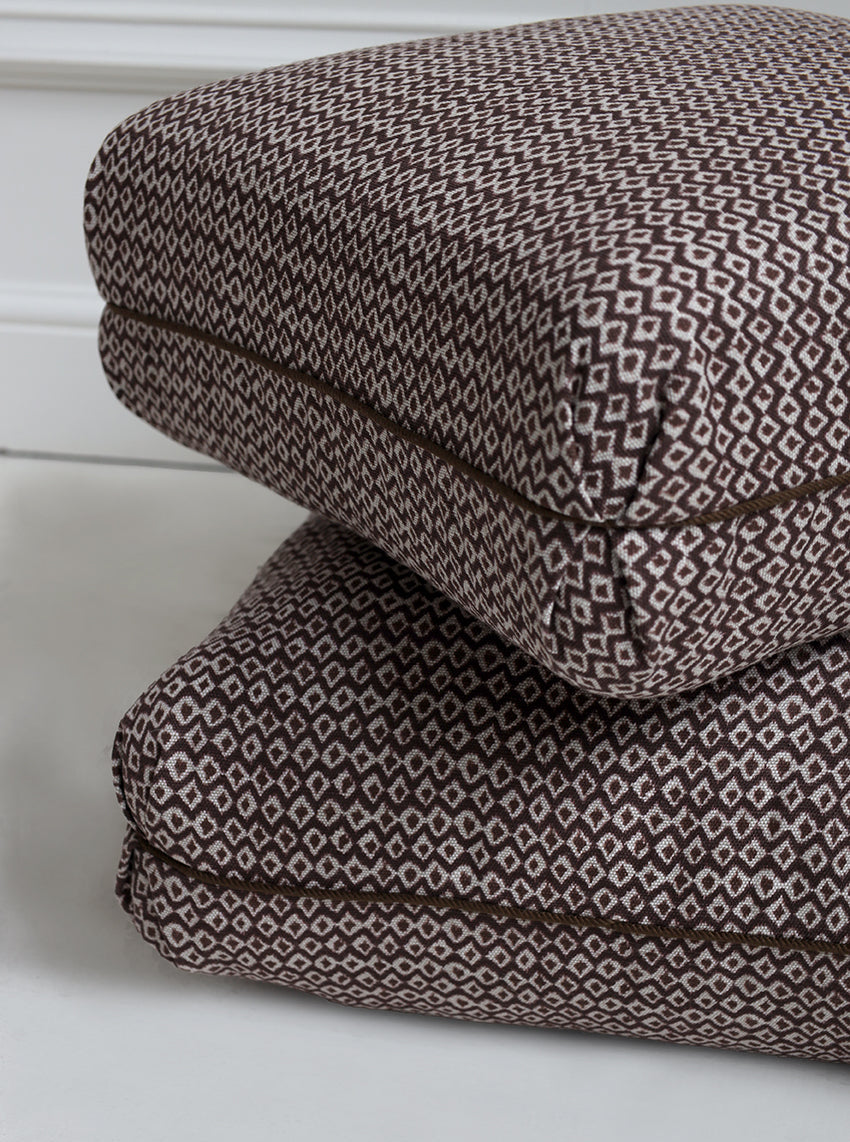 Two folded patterned blankets stacked on a white surface