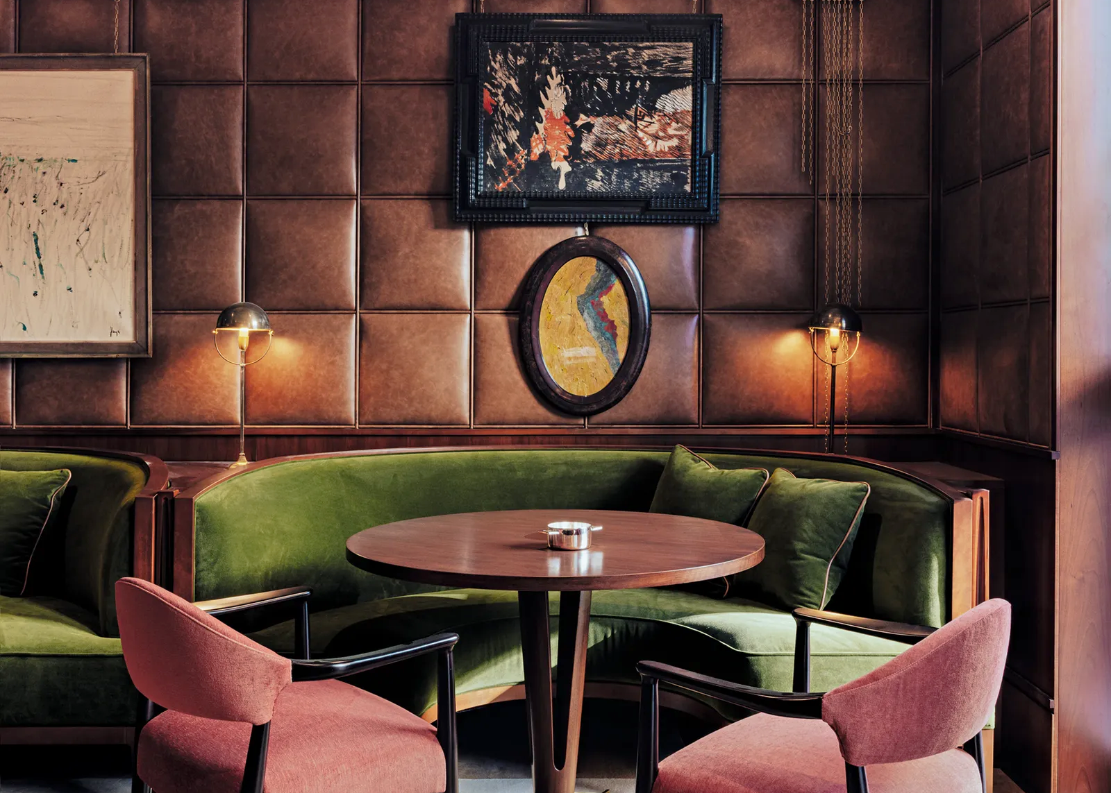 Cozy interior with green velvet couches, pink chairs, and a wooden table.