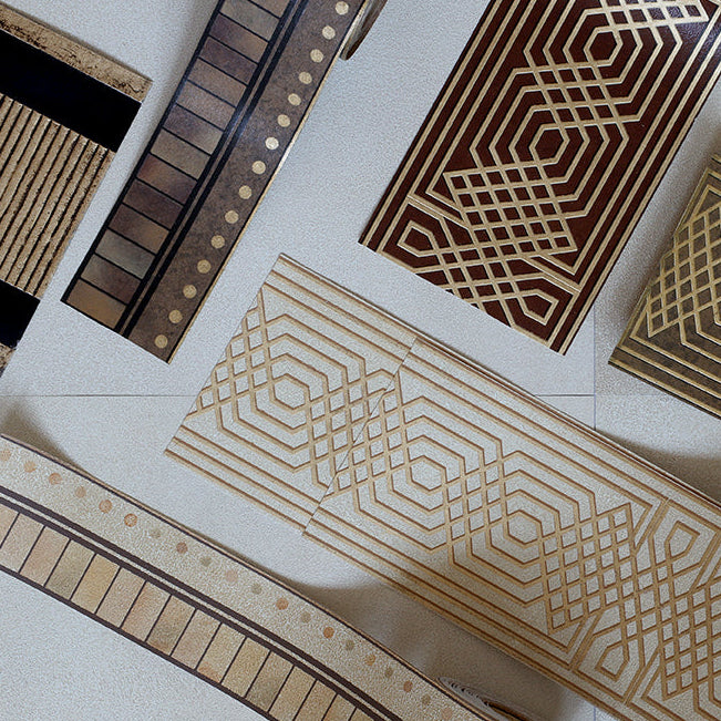 Several decorative wooden strips or boards with geometric and striped patterns are arranged on a light floor. The pieces show natural wood tones ranging from light tan to dark brown, with black accents on some ends.