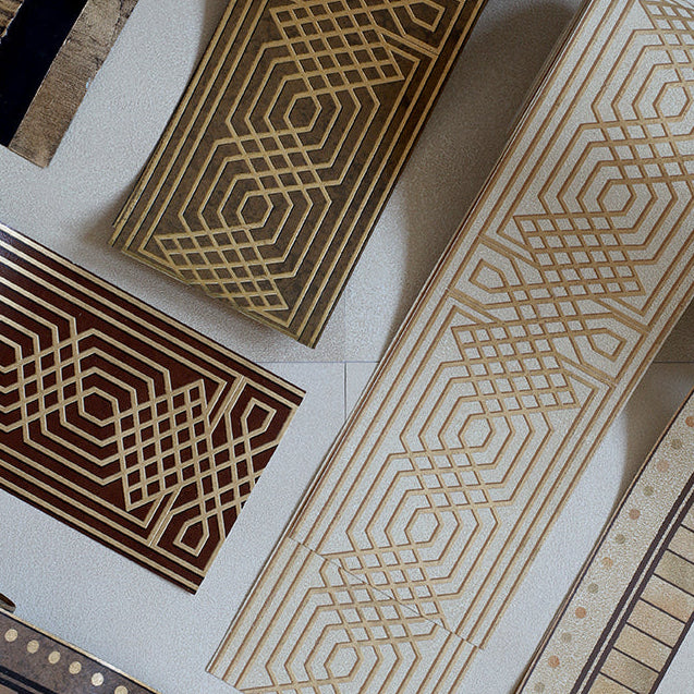 Several rectangular wooden boards with geometric inlay patterns in beige, brown, and black are arranged on a light neutral background.