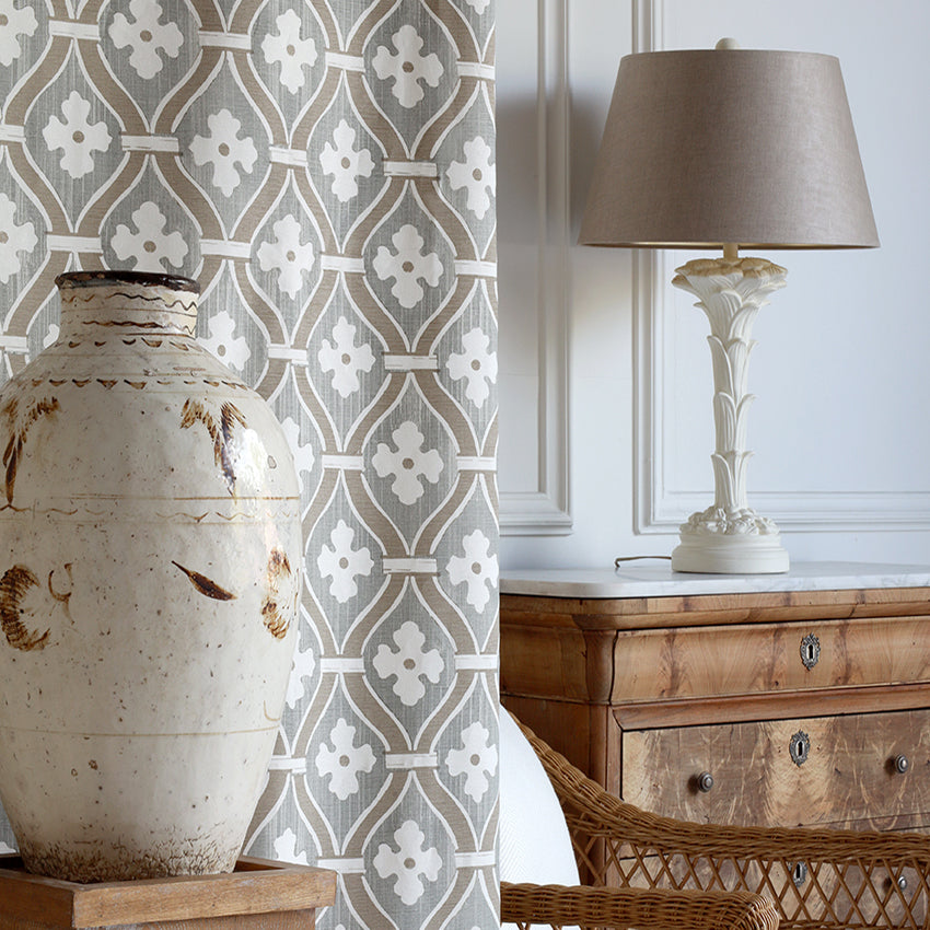 Decorative vase, lamp, and wooden furniture with a patterned curtain in a room setting.