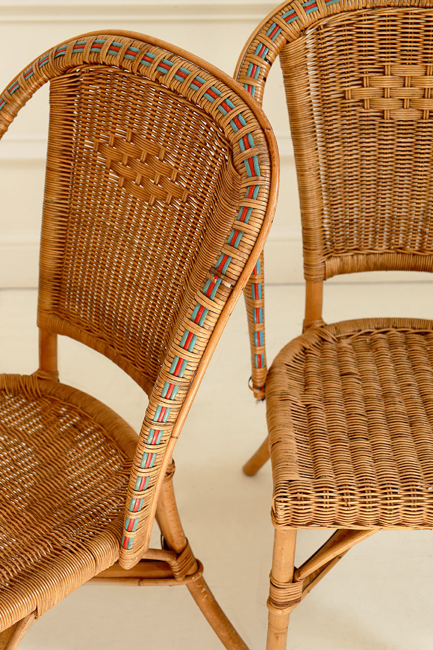 Two wicker chairs with a decorative armrest on a light background