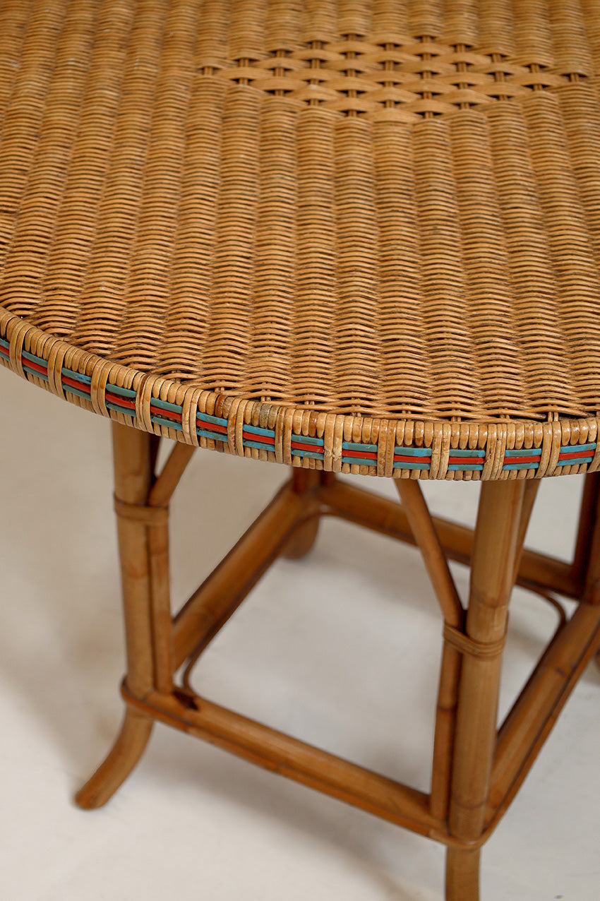 Close-up of a wicker table with a woven top and wooden legs on a plain background
