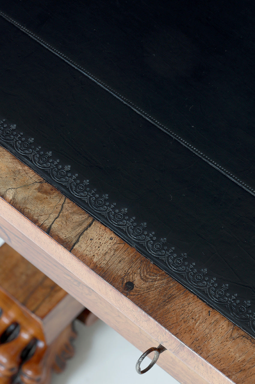 Black velvet fabric with intricate stitching on a wooden surface