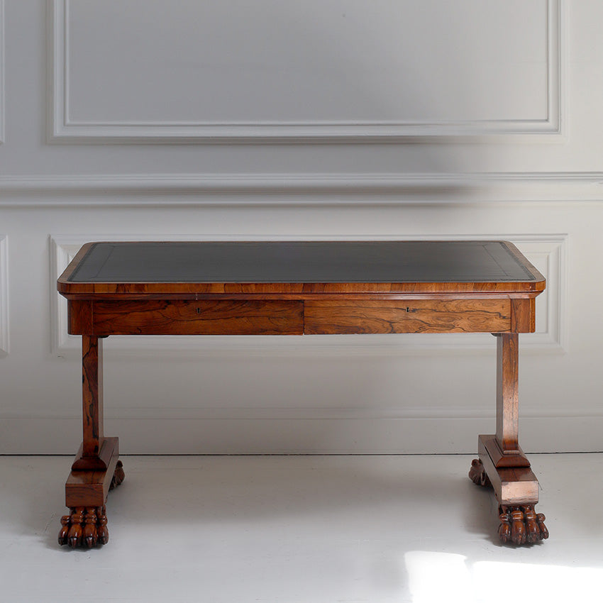 Wooden desk with a black leather top against a white wall
