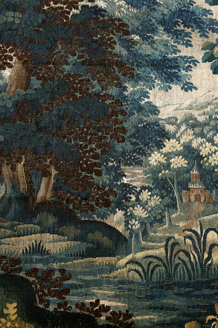 Detailed tapestry or fabric with a landscape design featuring trees, water, and buildings.