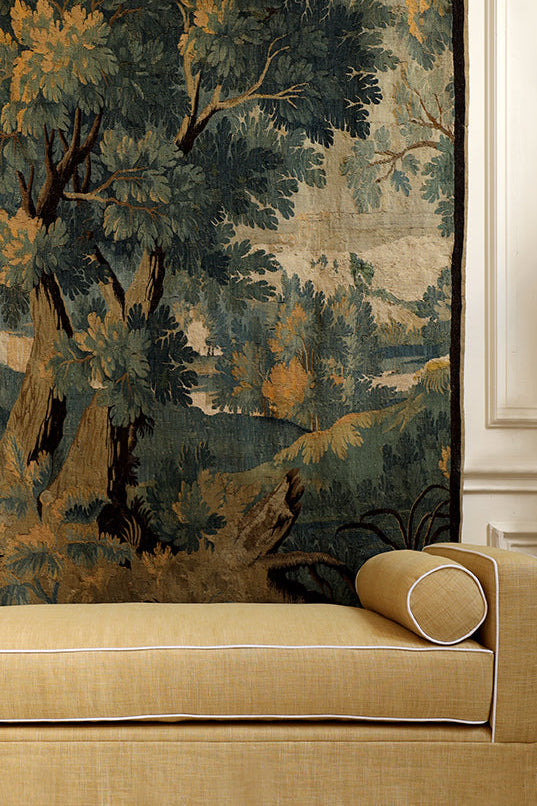 Decorative tapestry with a landscape design on a wall above a beige sofa.