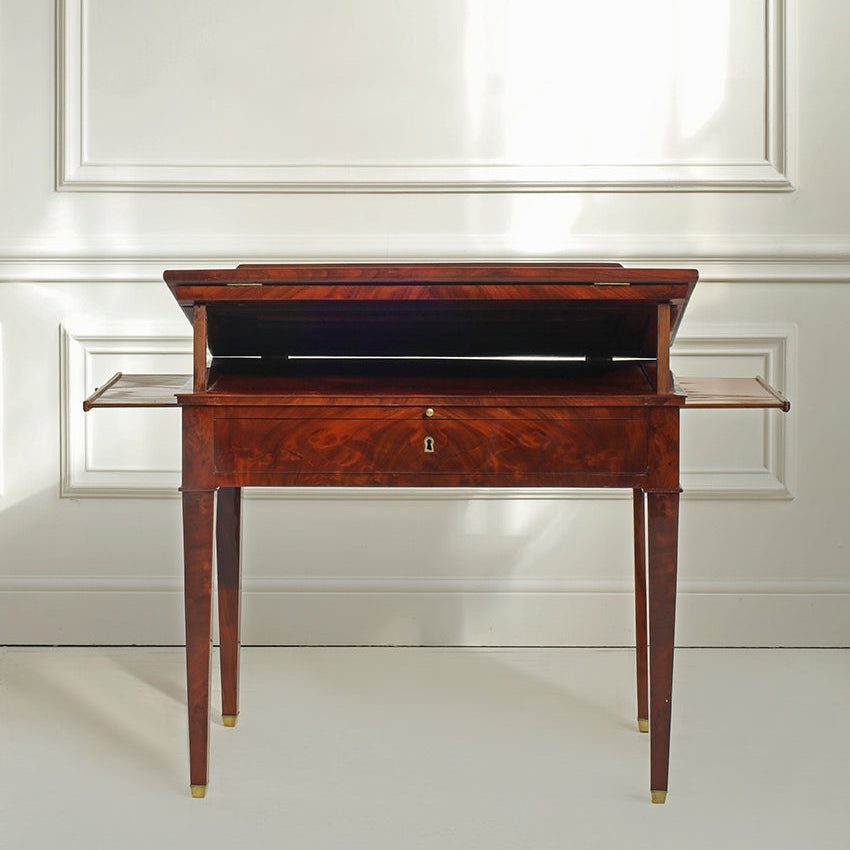 Wooden desk with a black top against a white wall