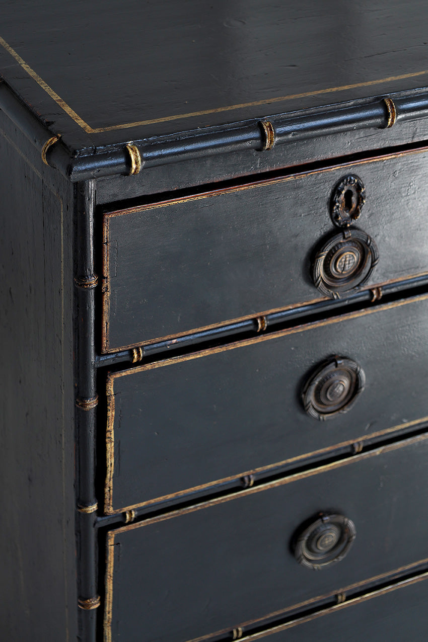 Close-up of a dark wooden dresser with brass handles and trim.