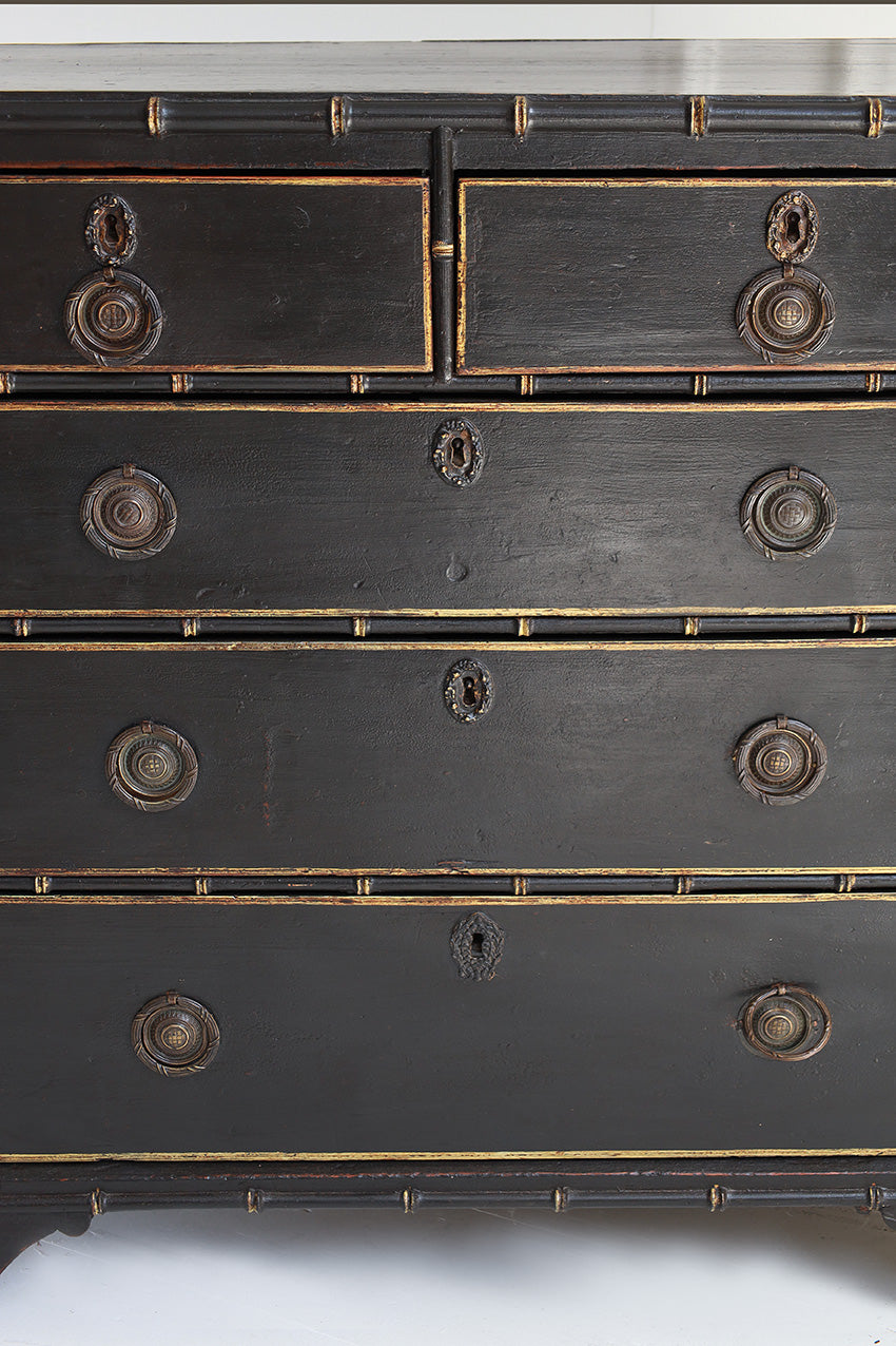 Close-up of a black dresser with gold accents on a white background