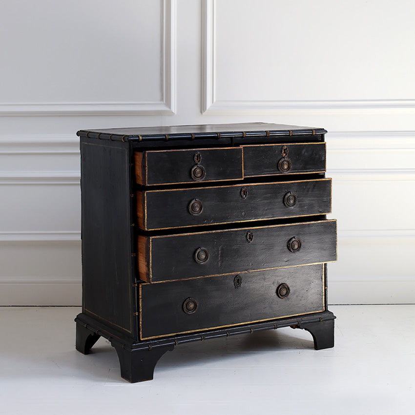Black chest of drawers with gold accents on a white background
