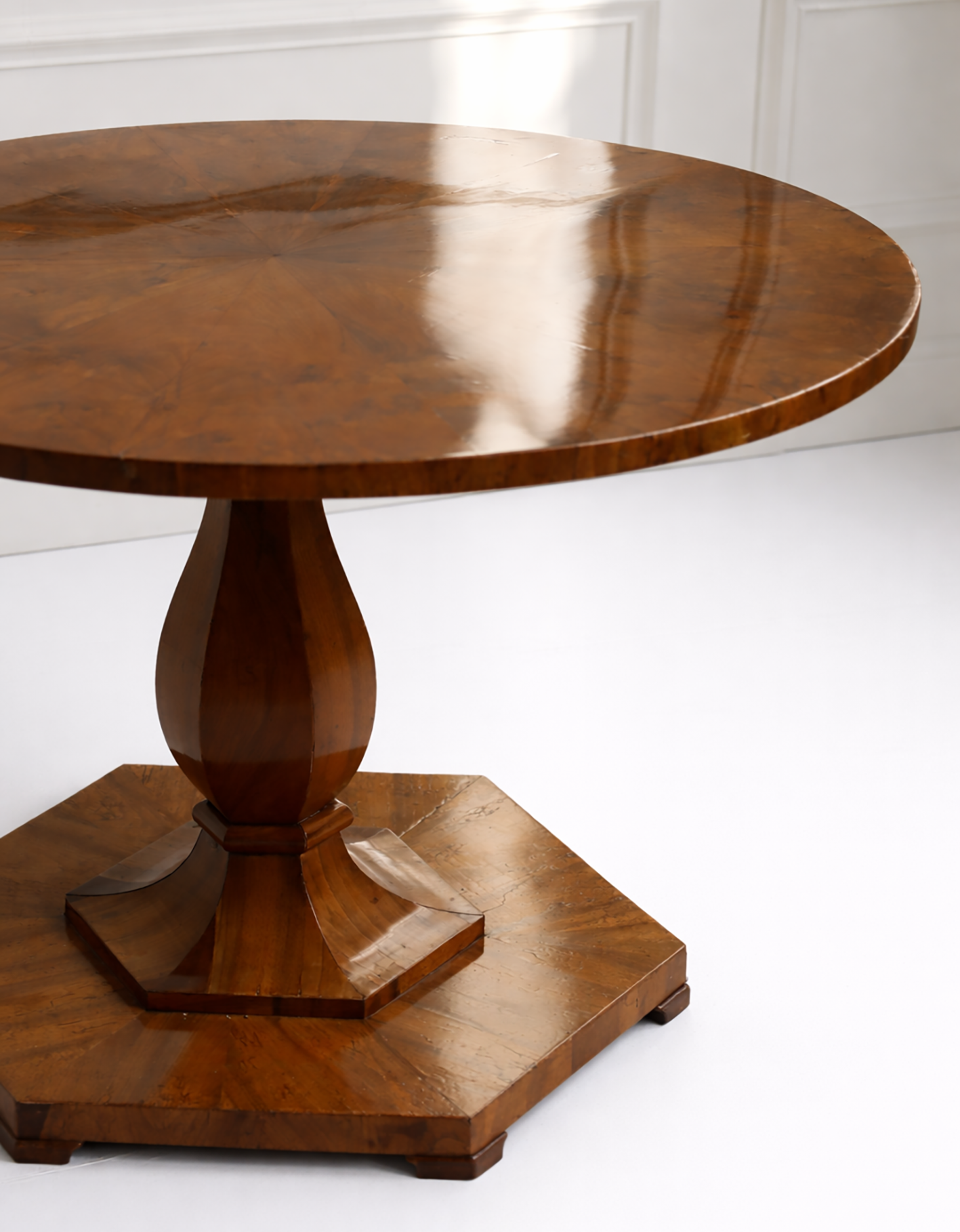 Wooden pedestal table against a white wall