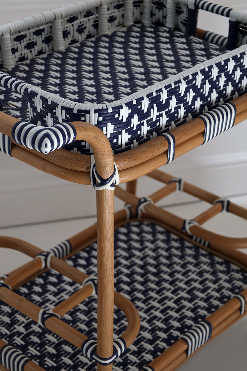 Rattan chair with navy and white geometric patterned cushions on a light wooden floor.