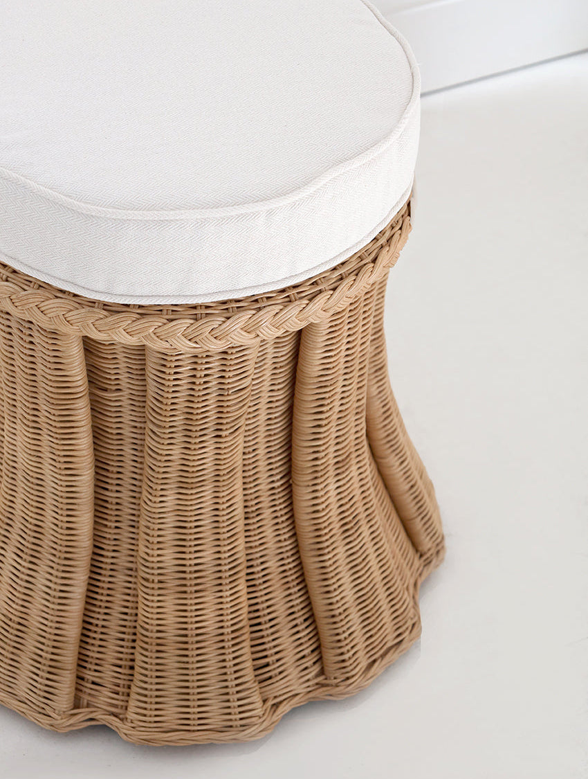 handcrafted wicker stool with a white cushion on a light wooden floor