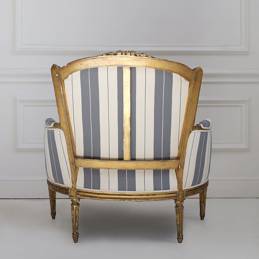 Striped armchair with wooden frame against a white wall