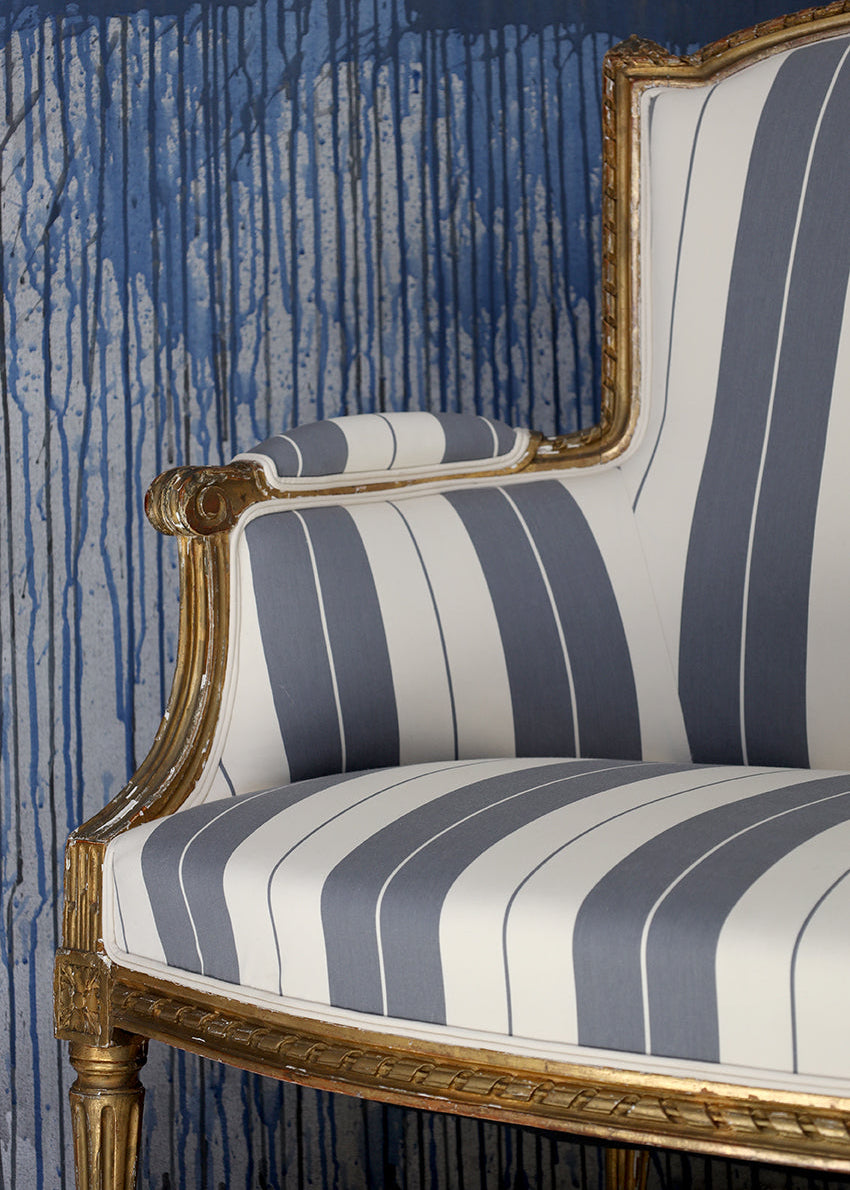 Striped chair with gold frame against a blue textured wall