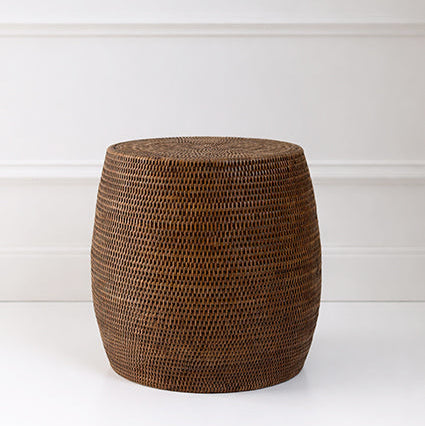 Woven brown stool against a white wall