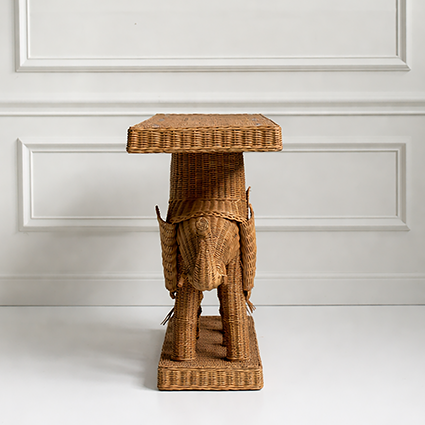 Wicker side table against a white paneled wall