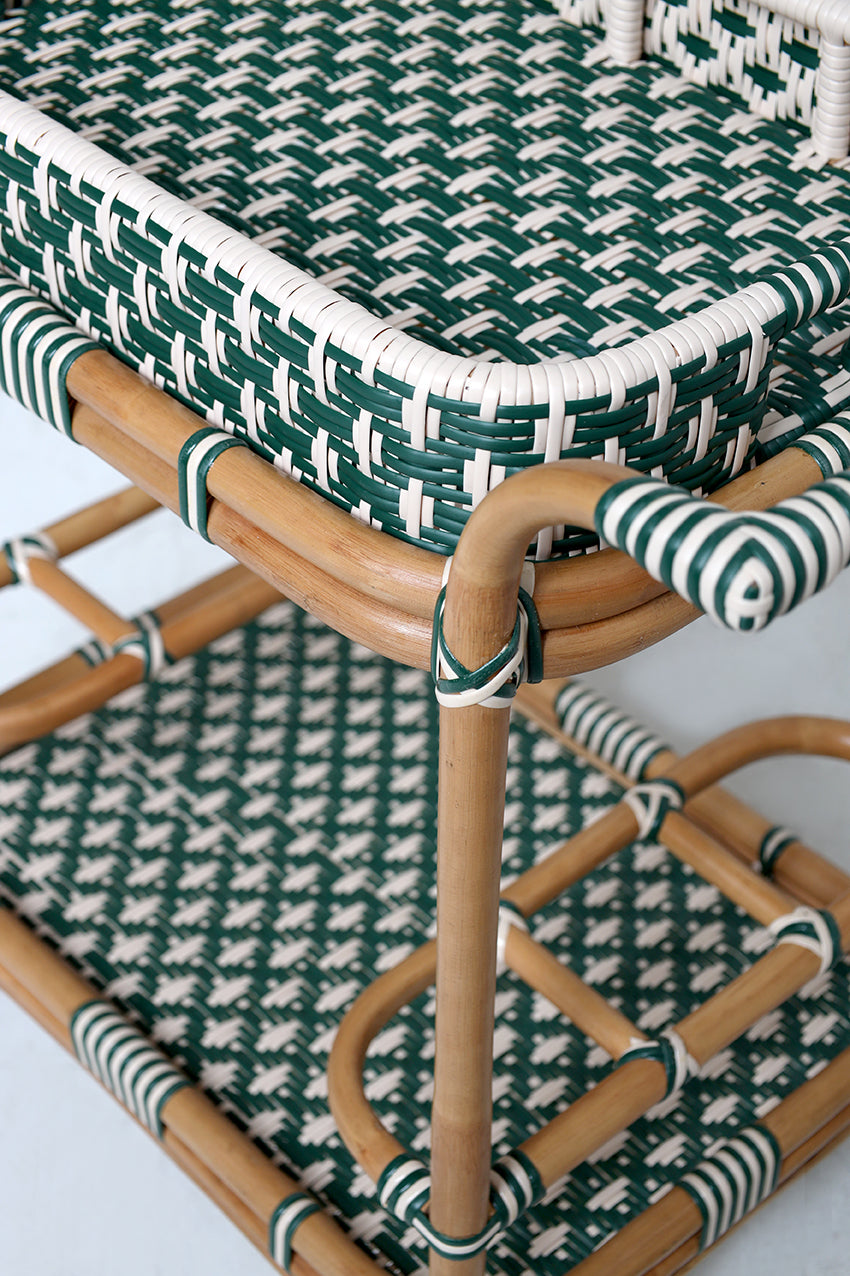 Rattan chair with green and white patterned cushions on a light background