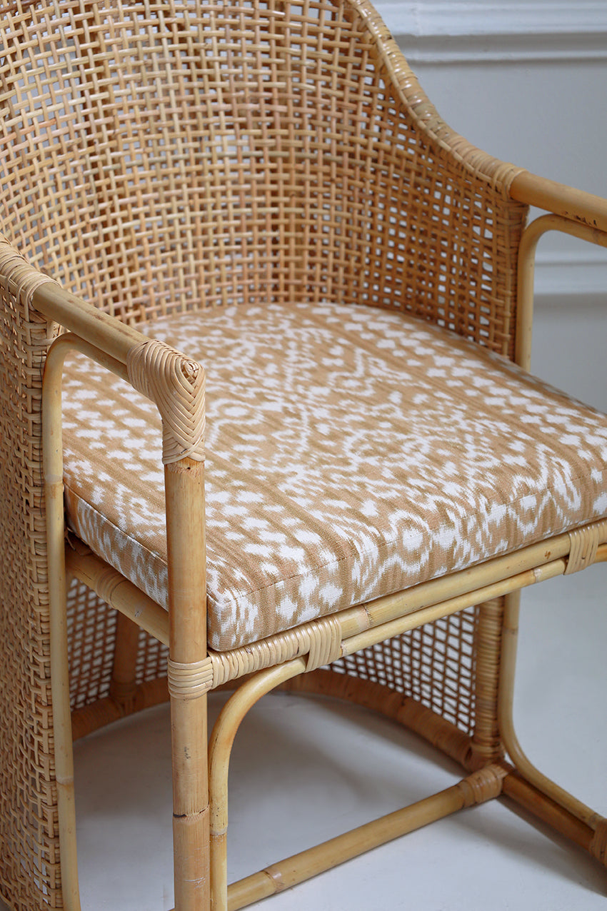 Wicker chair with patterned cushion on a white floor