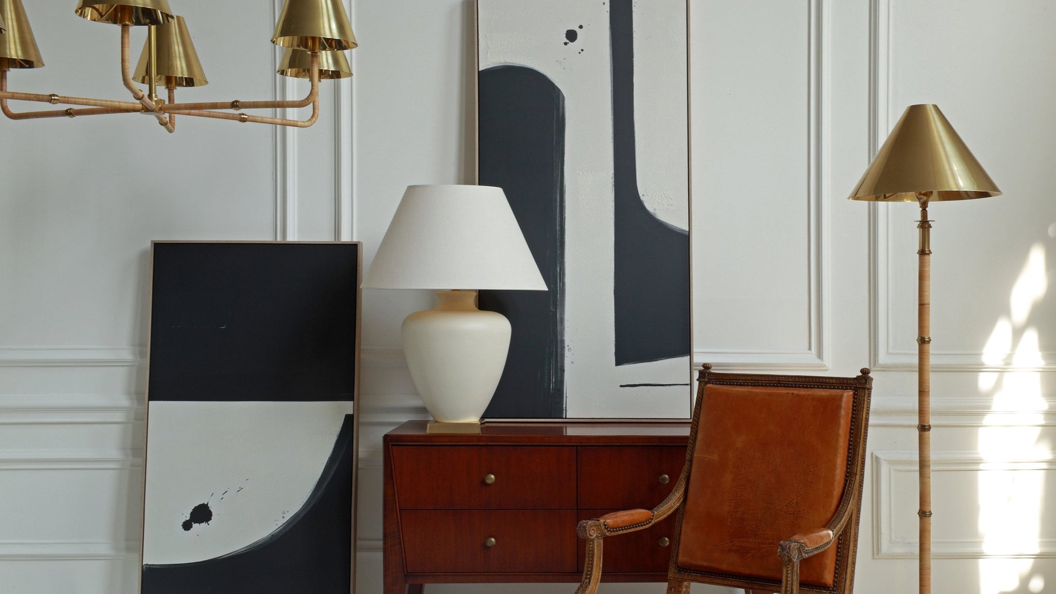 Modern interior with a brown leather chair, lamp, and abstract art on a white wall.