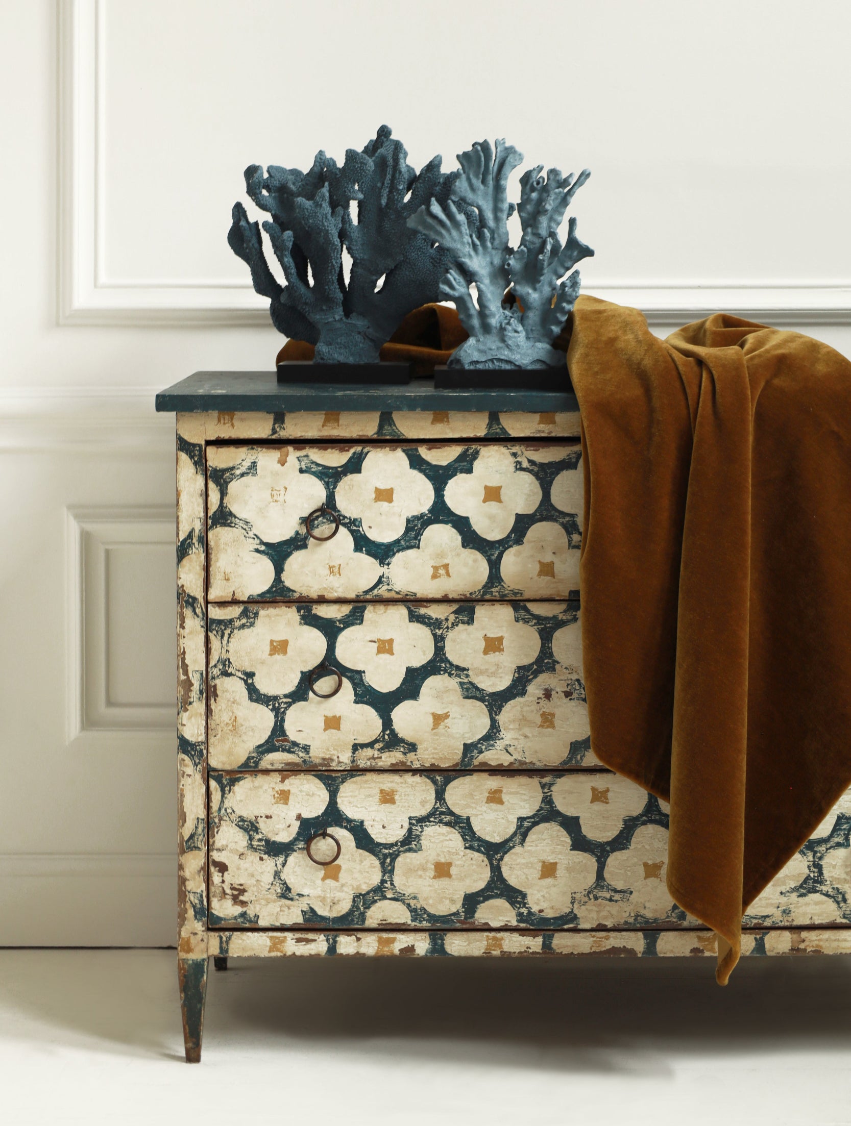 Decorative chest of drawers with floral pattern and blue coral sculpture on a white background