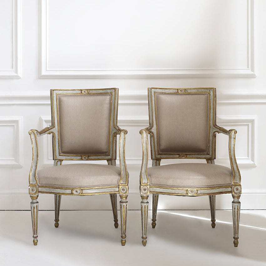 Two ornate chairs with gold accents against a white wall.