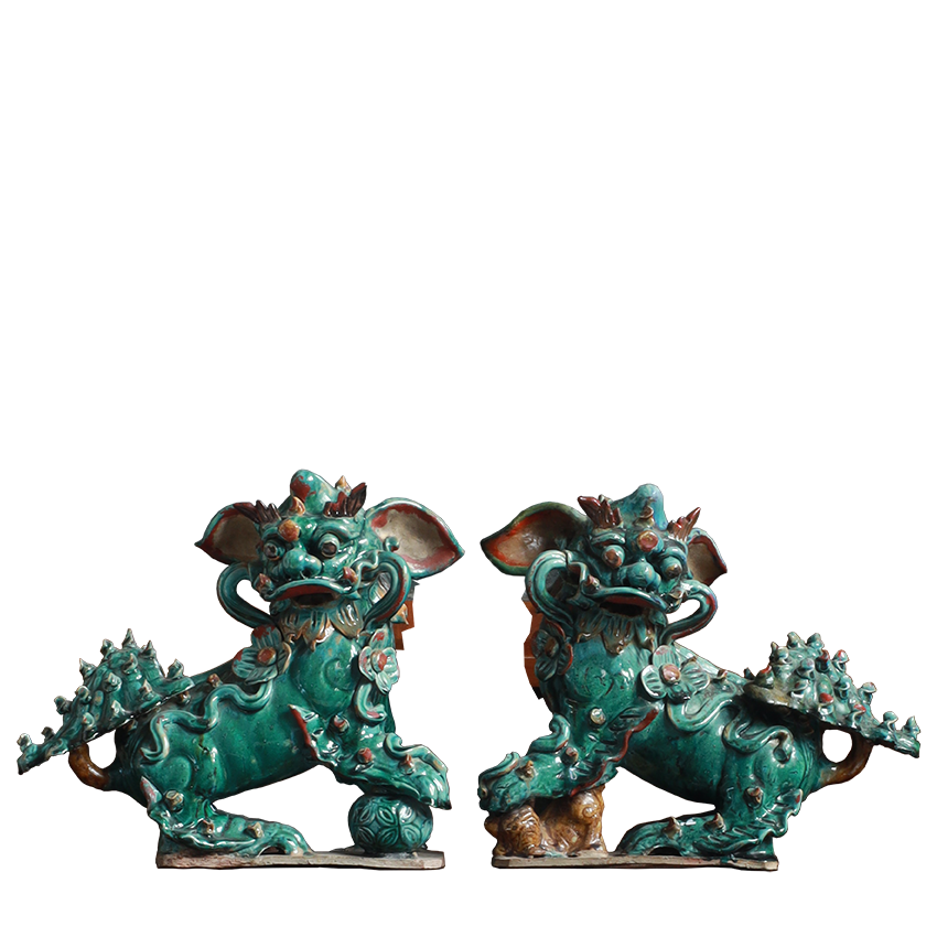 Pair of green ceramic lion statues on a white background