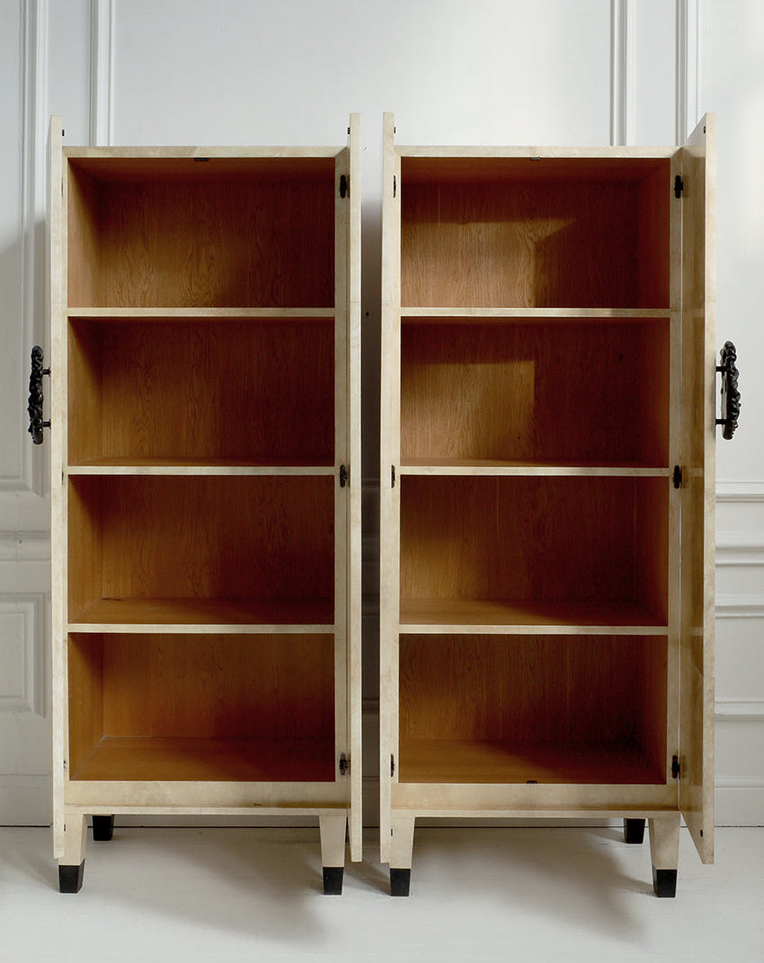 Two wooden cabinets with open doors on a white floor against a light-colored wall.