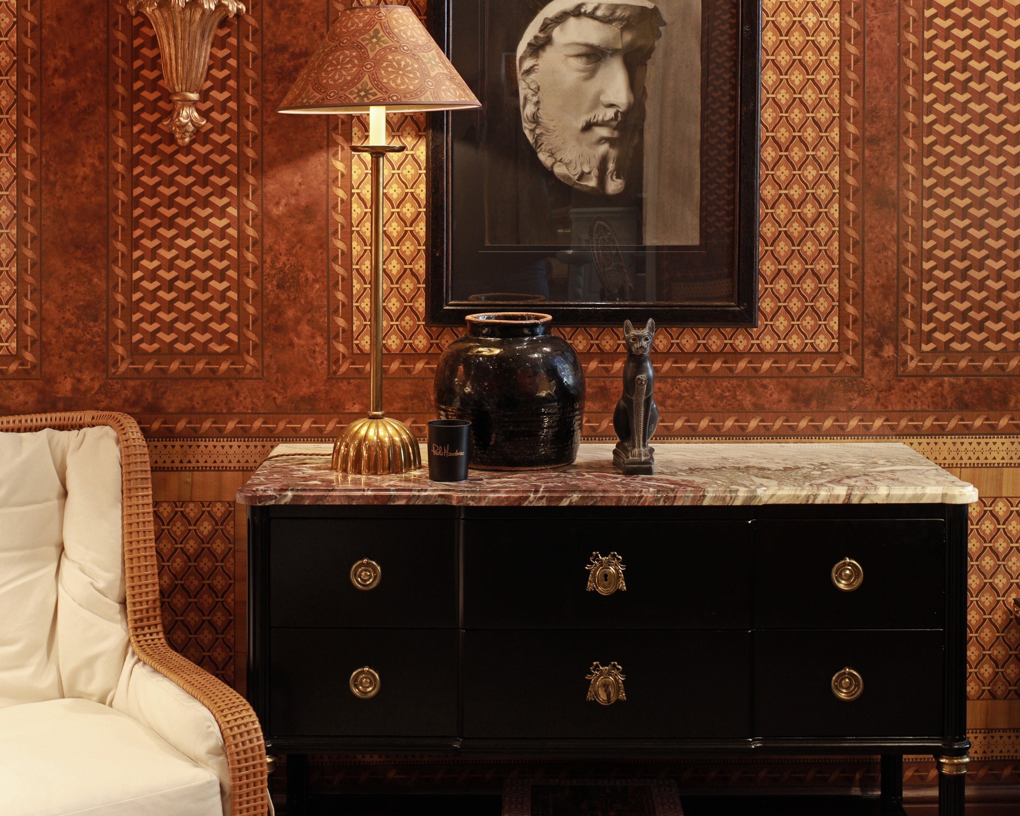 Decorative interior with a black dresser, wicker chair, and wall art.